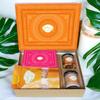 Ghasitaram Gifts Jaiccha Holi- Sweets/Holi Hampers/Thandai Ghasitaram Orange Hamper Box with Gujiyas, Thandai, Bhakarwadi, and Butter Chakli Pouch view 1