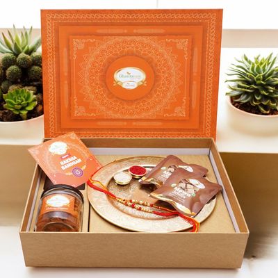 Ghasitaram Gifts Jaiccha Rakhi Gifts for Brothers Orange Hamper Box with Gold Pooja Thali, 2 rakhis, Card, MEWA Bites Pouches and Mixed Dryfruit Jar